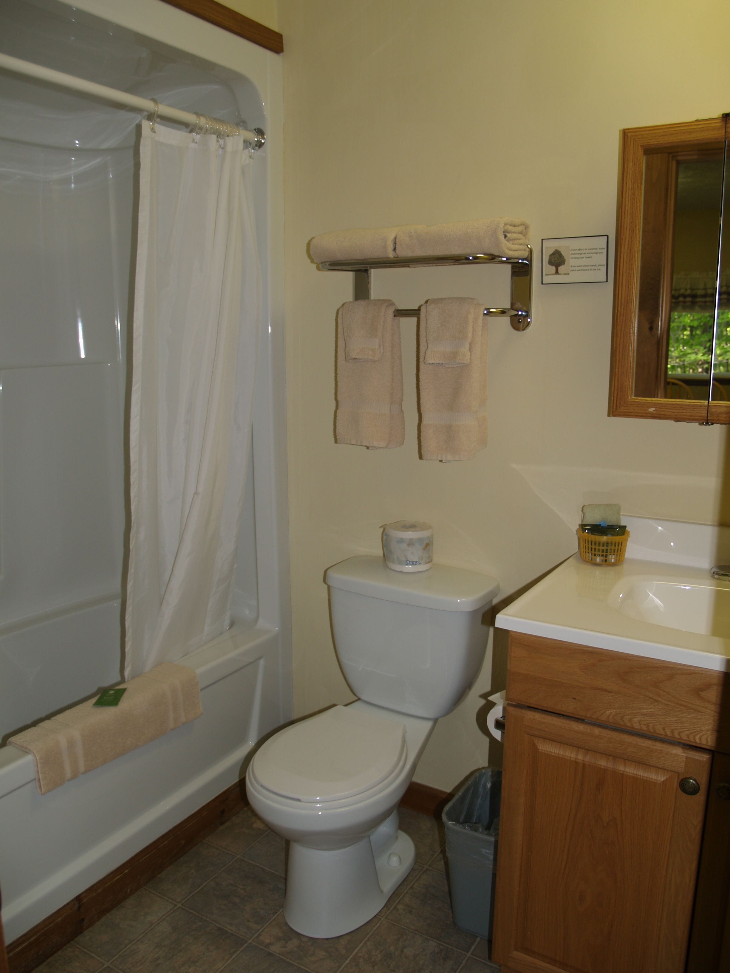 A bathroom with a bathtub, toilet, and wooden cabinet.
