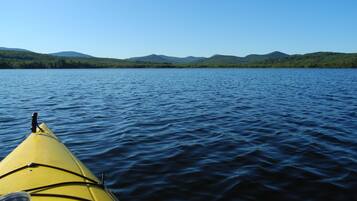 A kayak on calm water with a forested mountain range in the background.