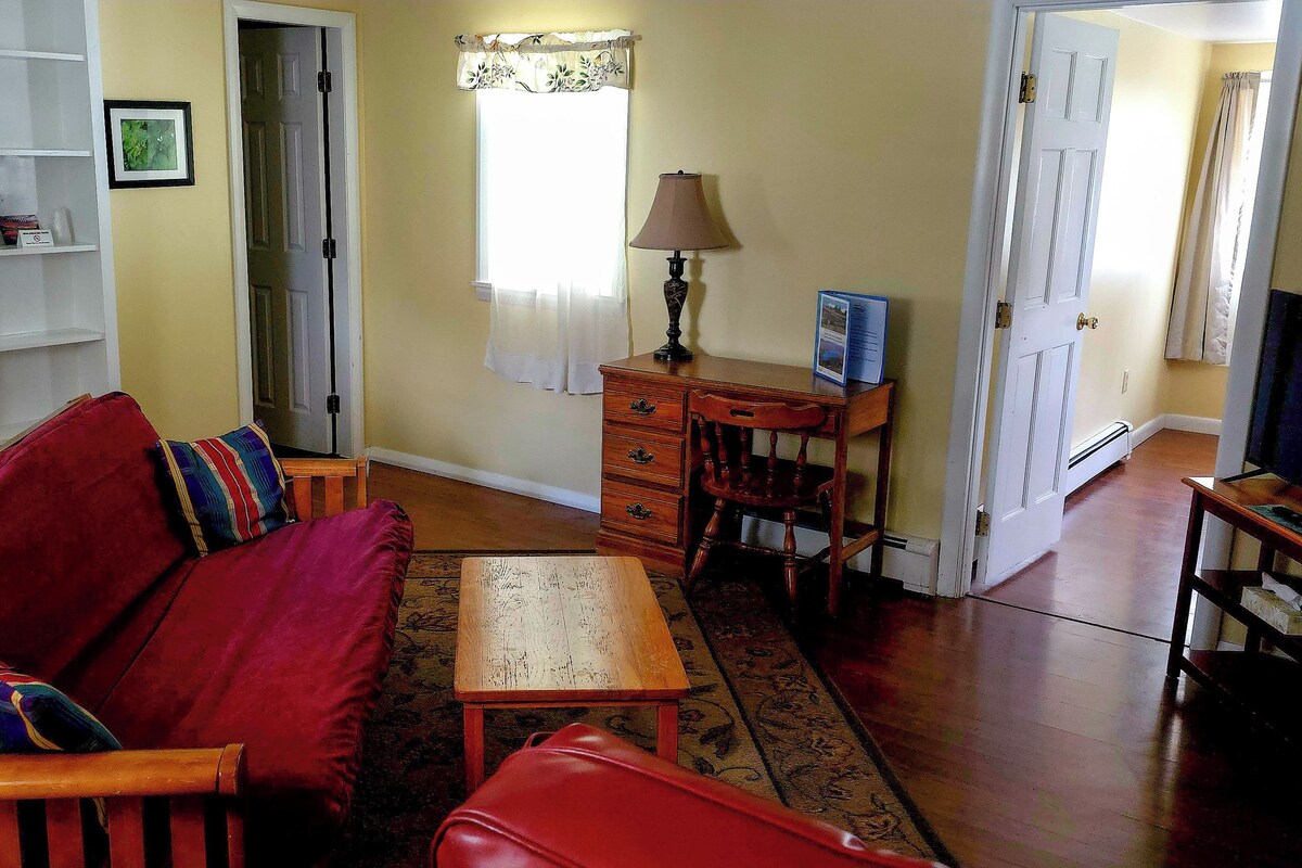 A living room with a red sofa, wooden coffee table, and a TV stand.