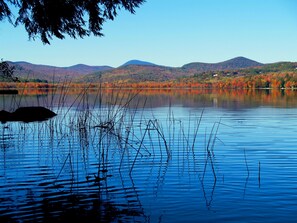 A calm lake with reflections of trees and mountains in the background.