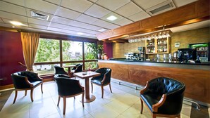 Un restaurante con zona de bar, sillas de madera y vistas a zonas verdes.