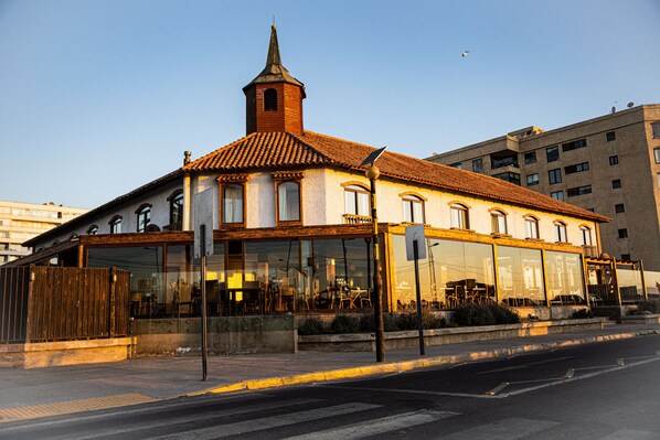 Un edificio con una torre destacada, ventanas amplias y una calle frente a él.