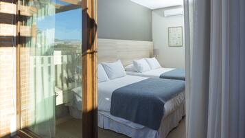 A hotel room with two beds, a large window, and a view of the city.