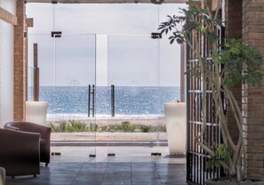 Un interior moderno con vistas al mar, que incluye una puerta de cristal, una zona de estar y una planta en maceta.