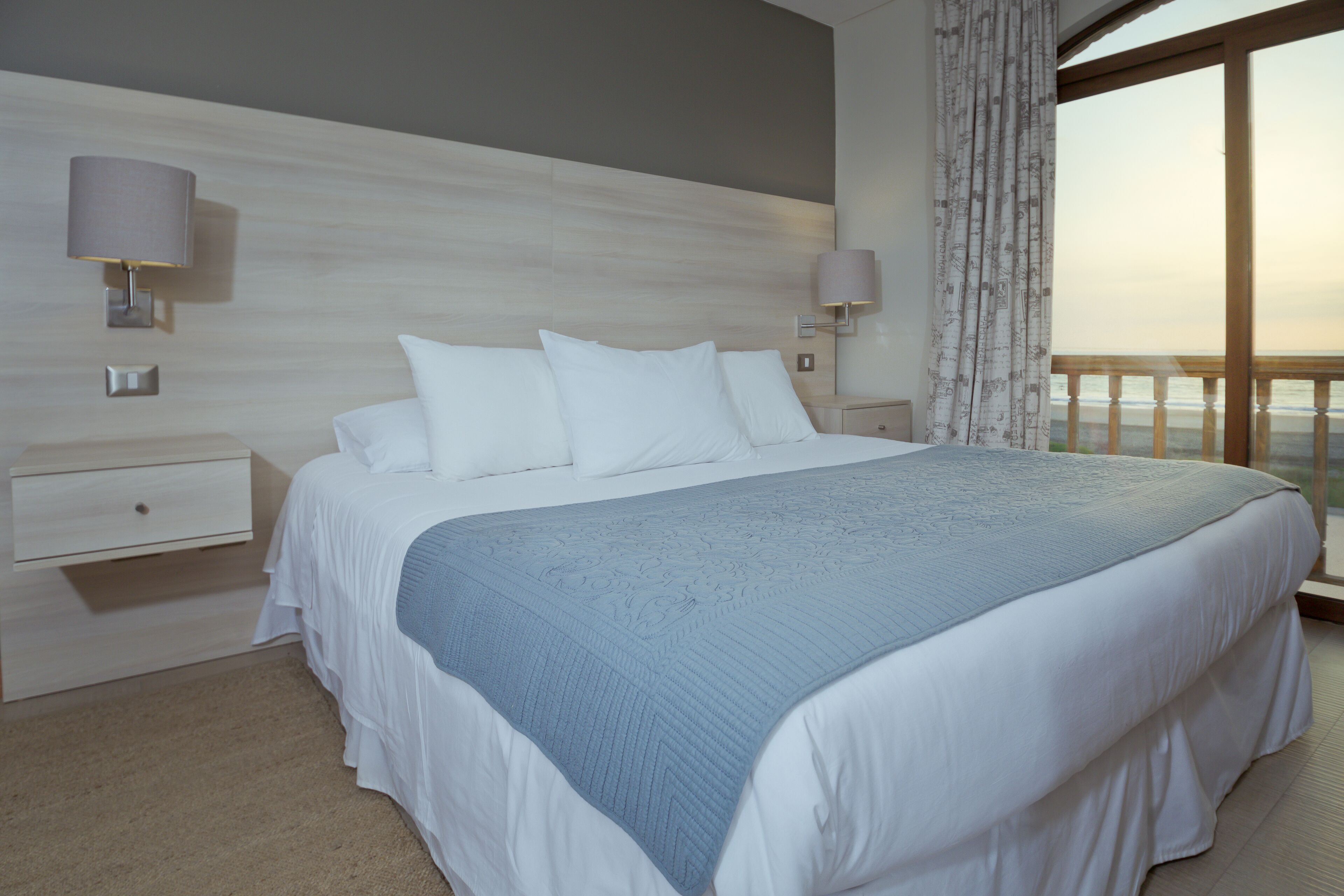 Ein Schlafzimmer mit einem großen Bett, zwei Nachttischen und Meerblick.