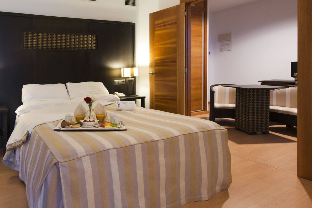 A hotel room with a bed, bedside tables, a desk, and a chair.