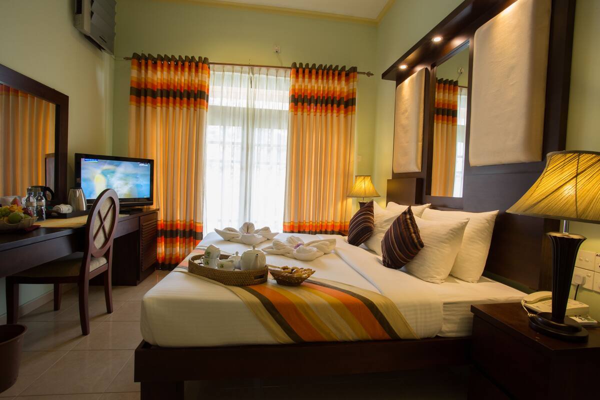 Ein Hotelzimmer mit einem Bett, einem Schreibtisch mit Fernseher, einer Lampe und einem Stuhl.