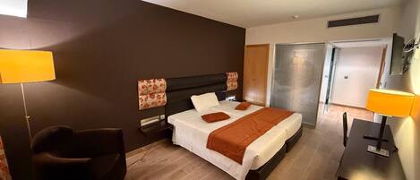 A hotel room with a bed, bedside tables, a chair, and a desk.