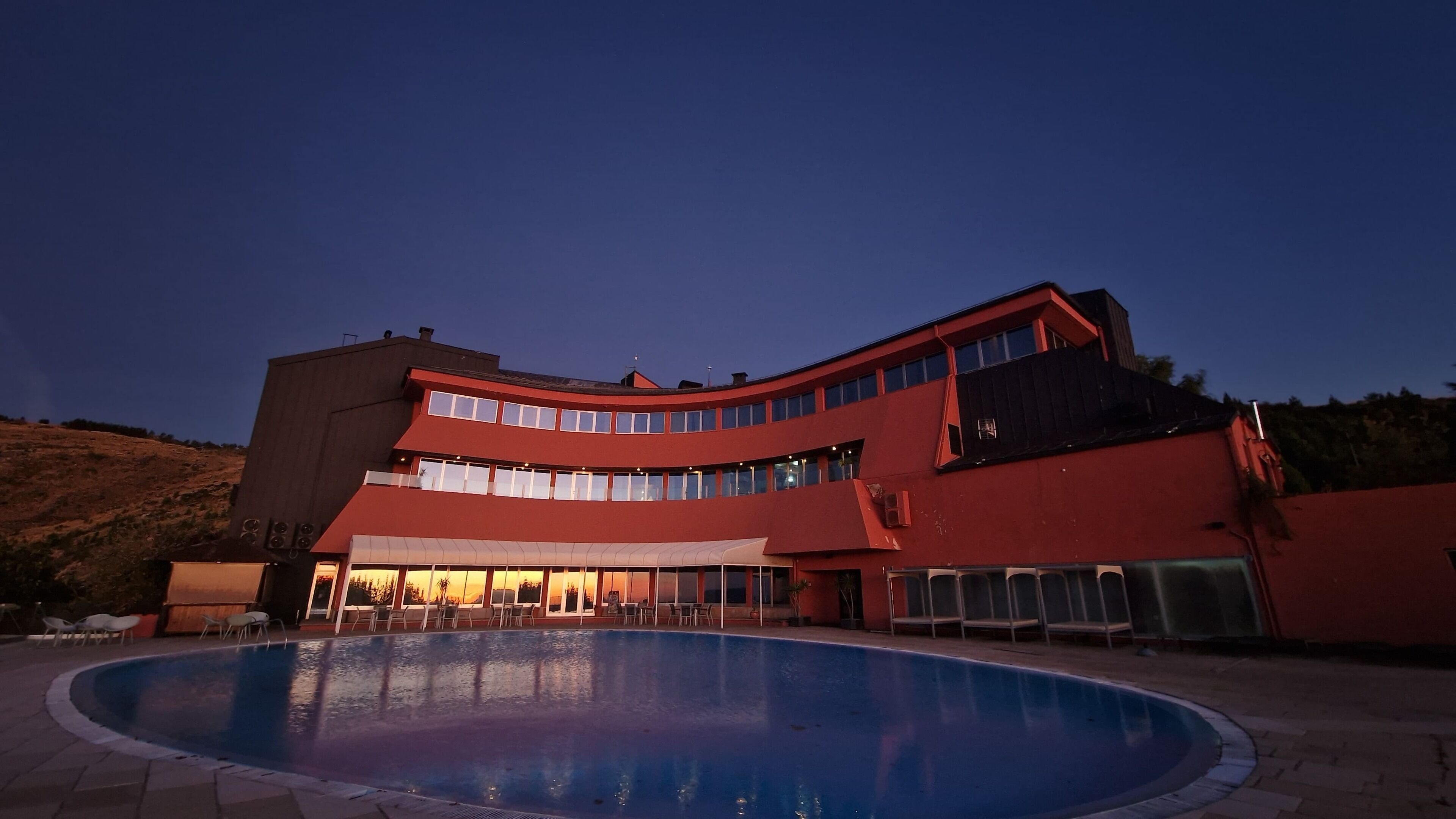 A large building with a swimming pool in front.