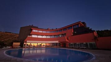 A large building with a swimming pool in front.