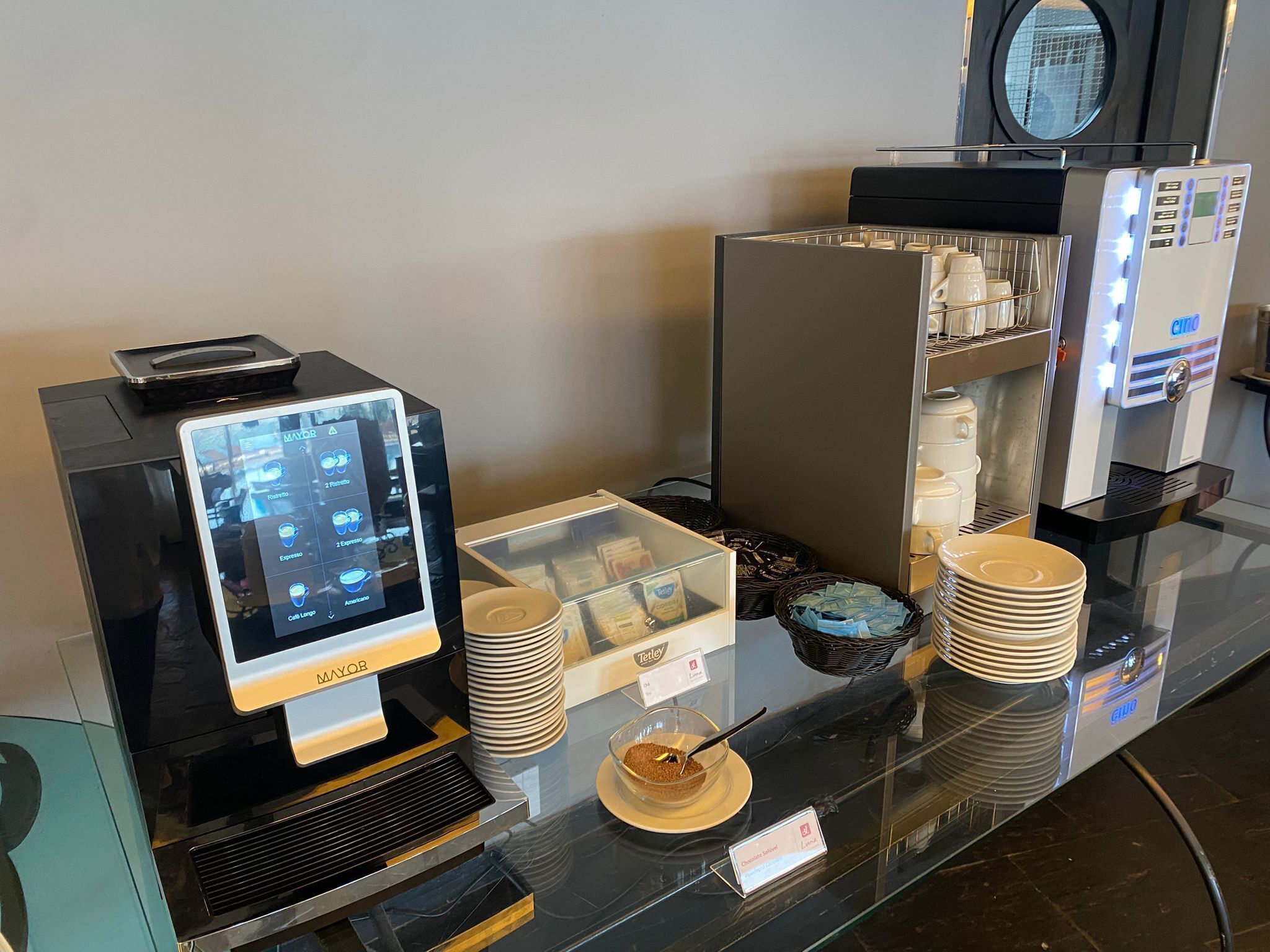 A coffee station with a digital menu display, a coffee machine, and a display case with pastries.
