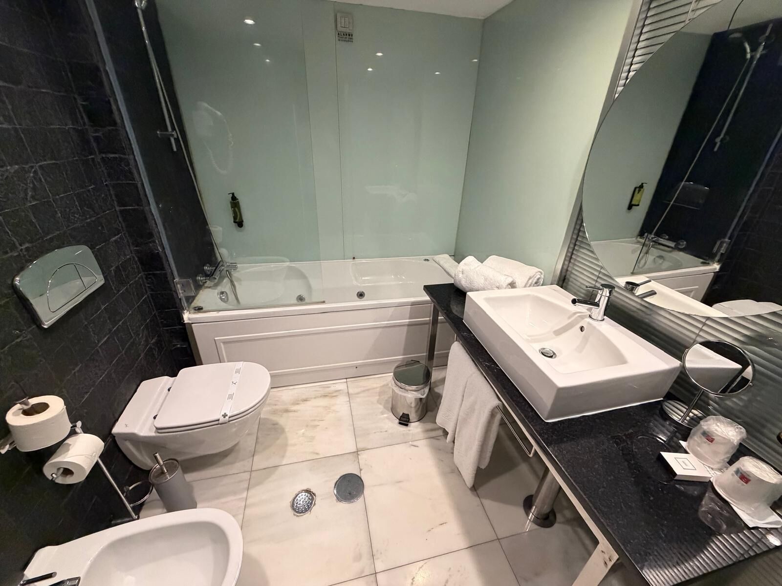 A modern bathroom with a bathtub, a toilet, a bidet, and a sink.
