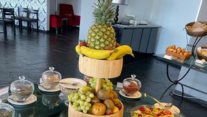 Una mesa de buffet con diversas frutas, una piña y un tazón de sandía.