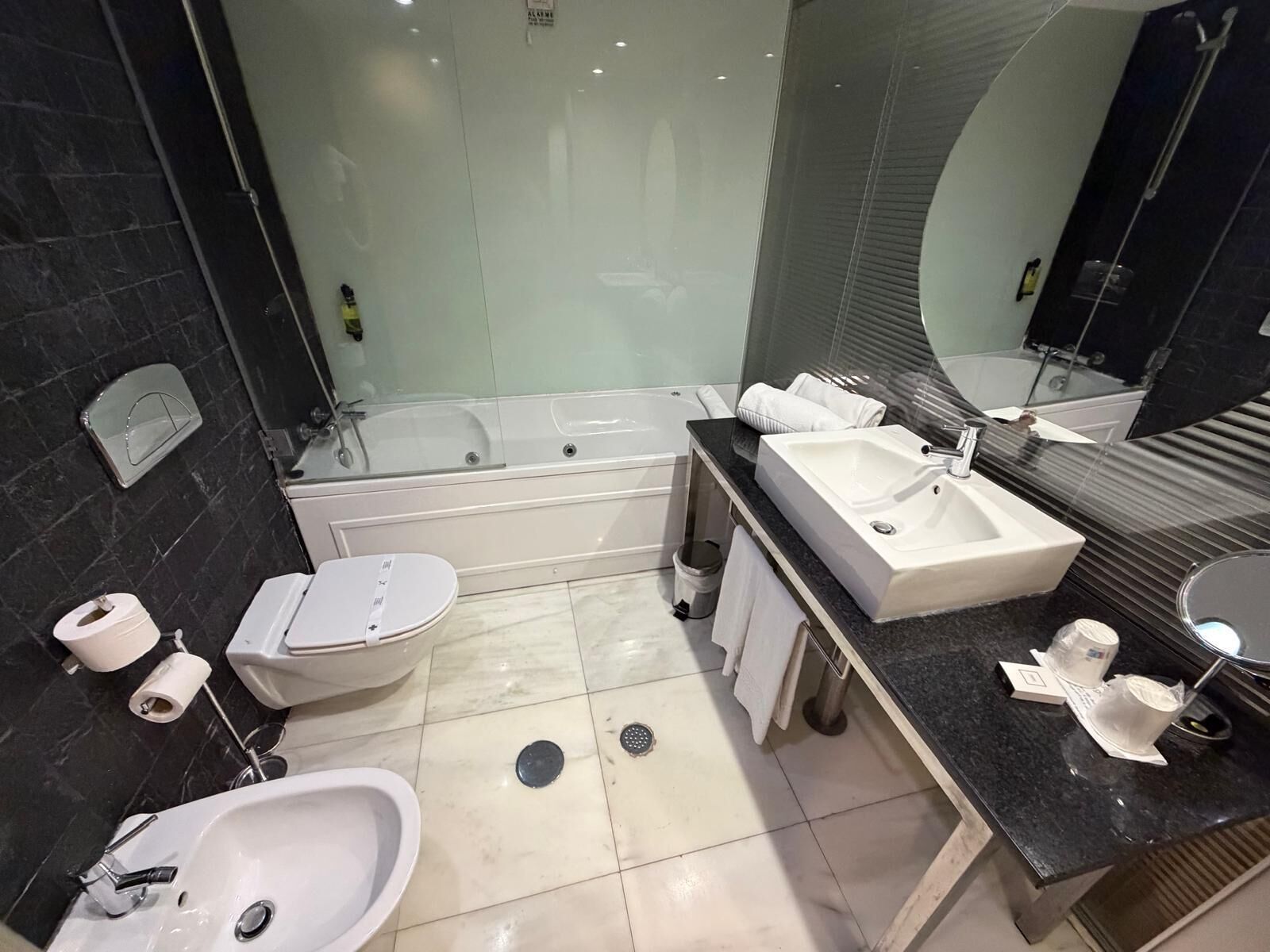A modern bathroom with a bathtub, two sinks, a toilet, and a shower.