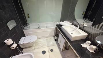 A modern bathroom with a bathtub, two sinks, a toilet, and a shower.