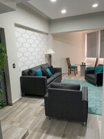 Una sala de estar moderna con un sofá gris, un sillón a juego y una pequeña mesa redonda con dos sillas.