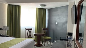 A hotel room with a bed, a small round table, a chair, a desk with a mirror, and a window with curtains. - Hotel Lois Veracruz (Boca del Río)