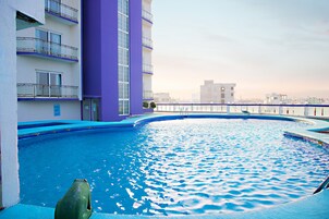 A rooftop swimming pool with a view of a cityscape.