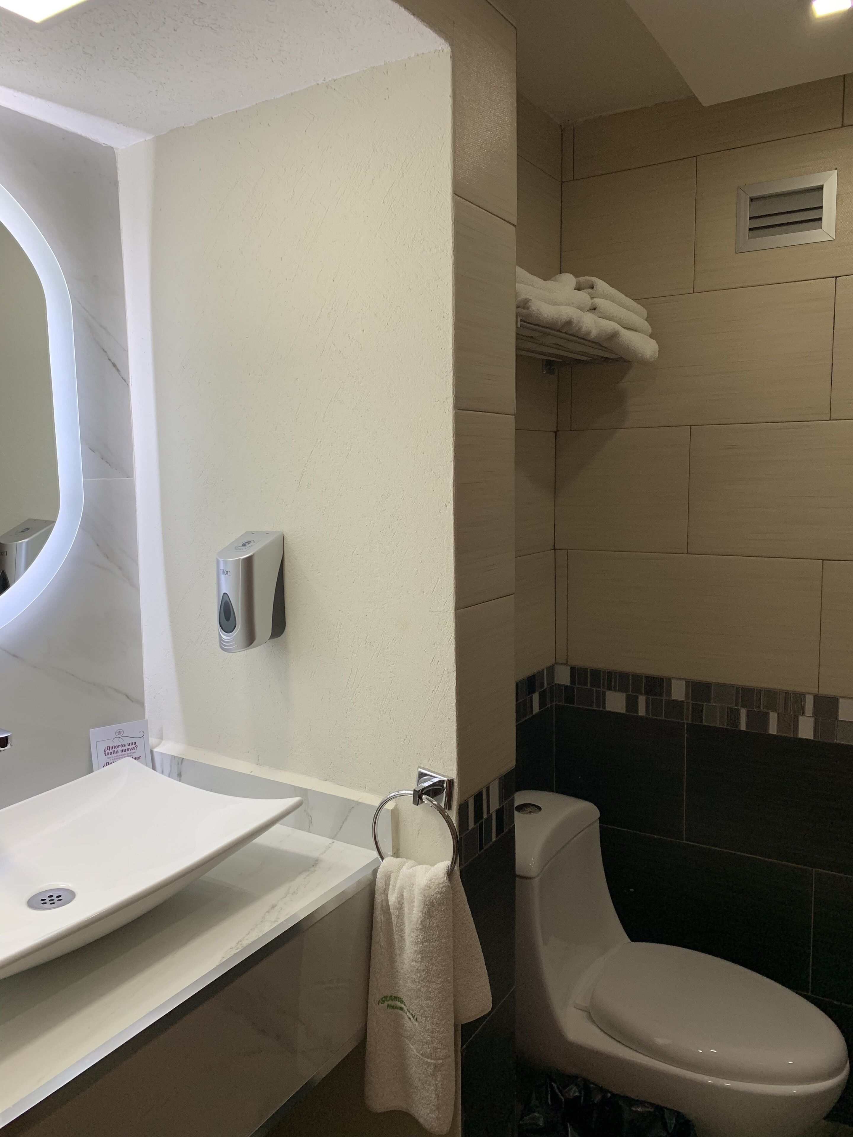 A bathroom with a white sink, a toilet, and a hand dryer.