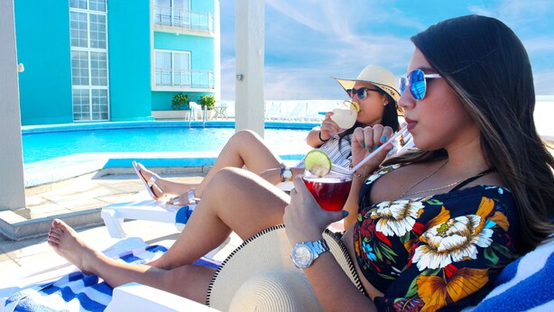 A poolside area with lounge chairs and a building with blue walls and windows. - Hotel Lois Veracruz (Boca del Río)
