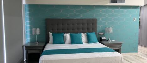 A modern bedroom with a large bed, two bedside tables, and a wall-mounted air conditioning unit.