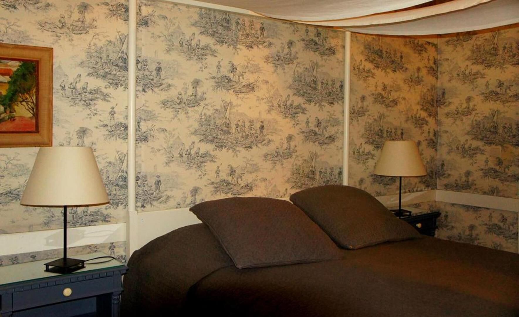 Un dormitorio con cama, dos mesitas de noche, lámparas y papel tapiz floral.