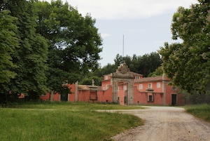 Un edificio rojo con un gran arco y un asta de banderas al frente.