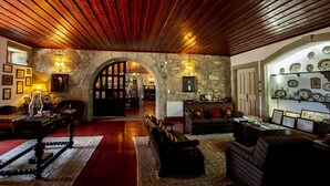 A spacious lobby with a stone archway, wooden ceiling, and various seating arrangements. - Casa Do Cimo (Fundao)