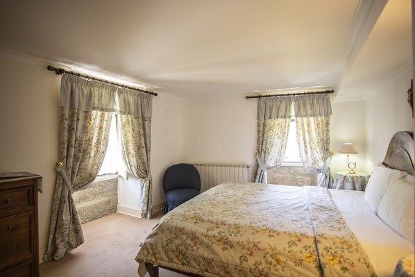 A bedroom with a bed, a chair, a dresser, and curtains. - Casa Do Cimo (Fundao)