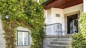 A stone staircase leading to a building with a white facade and a green roof. There are three terracotta pots on the steps. - Casa Do Cimo (Fundao)