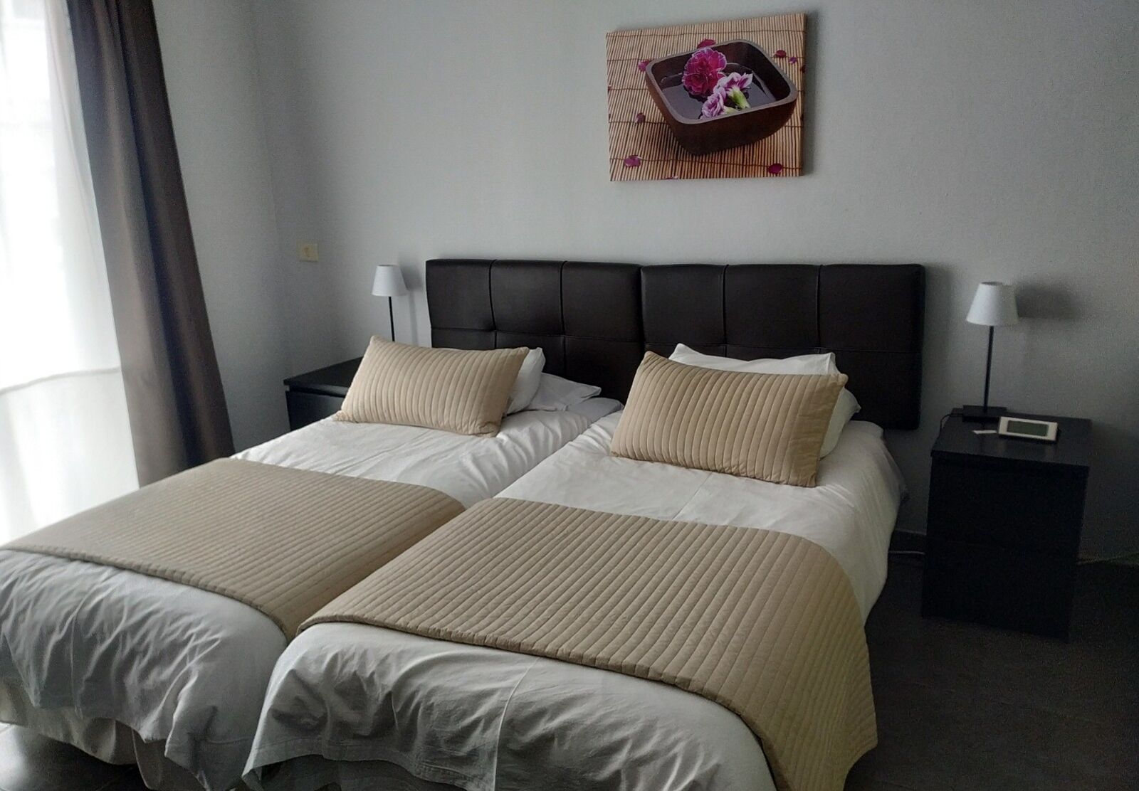A hotel room with a double bed, two bedside tables, and a wall-mounted artwork.