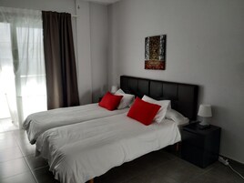 Una habitación de hotel con dos camas, una mesita de noche, una lámpara y un cuadro en la pared.