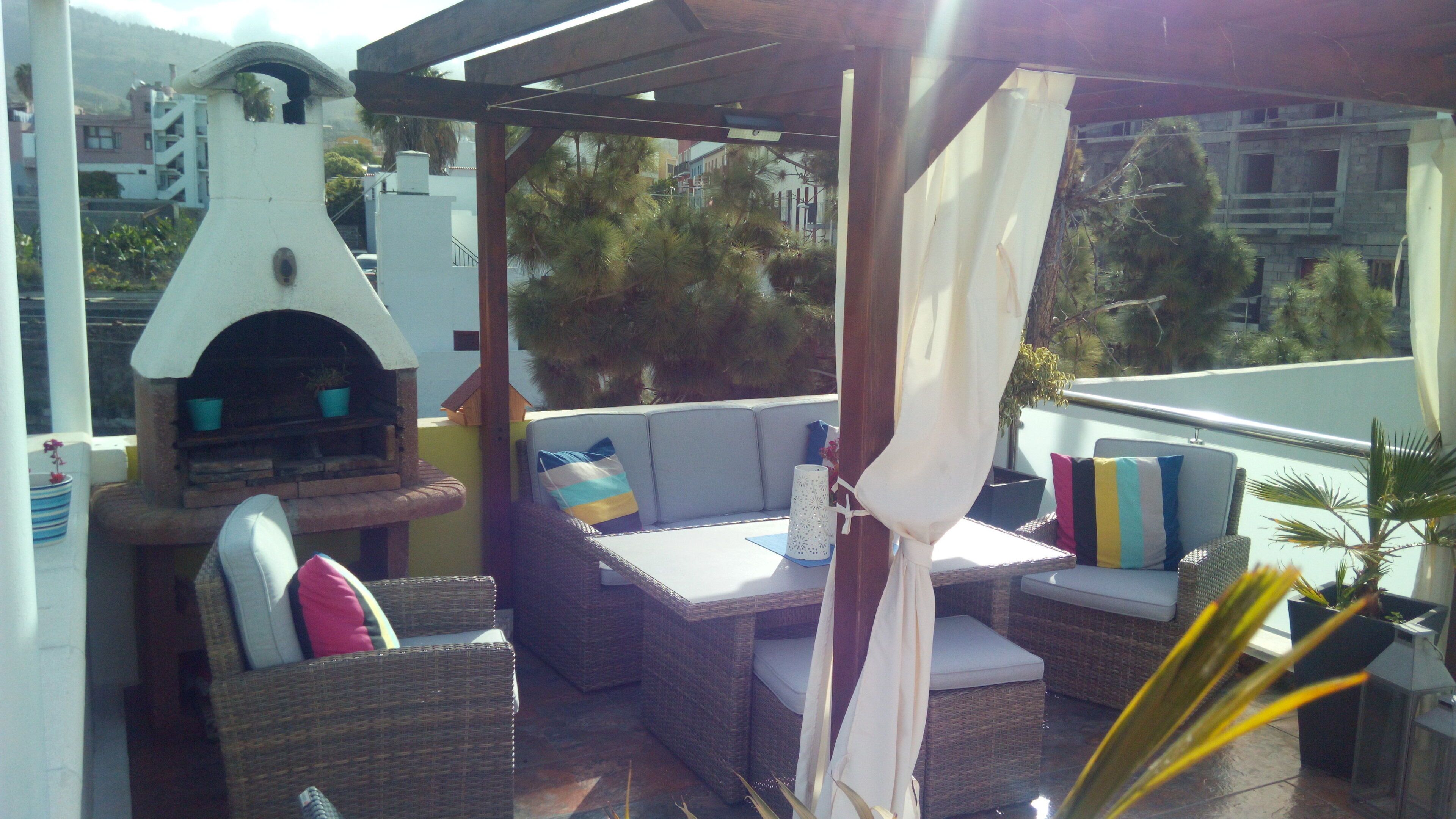 En terrasse med indbygget grill, fletmøbler og udsigt over byen.