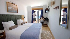 A hotel room with a large bed, a desk, and a mirror.