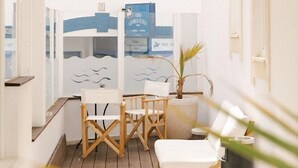 A sunlit room with a wooden floor, a white sofa, and a small table. - Camarao (Mafra)