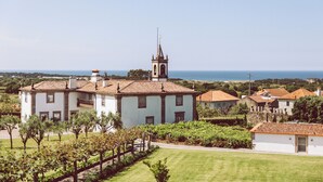 A large building with a bell tower, surrounded by well-maintained gardens and a view of the sea. - Quinta Do Monteverde (Viana do Castelo)