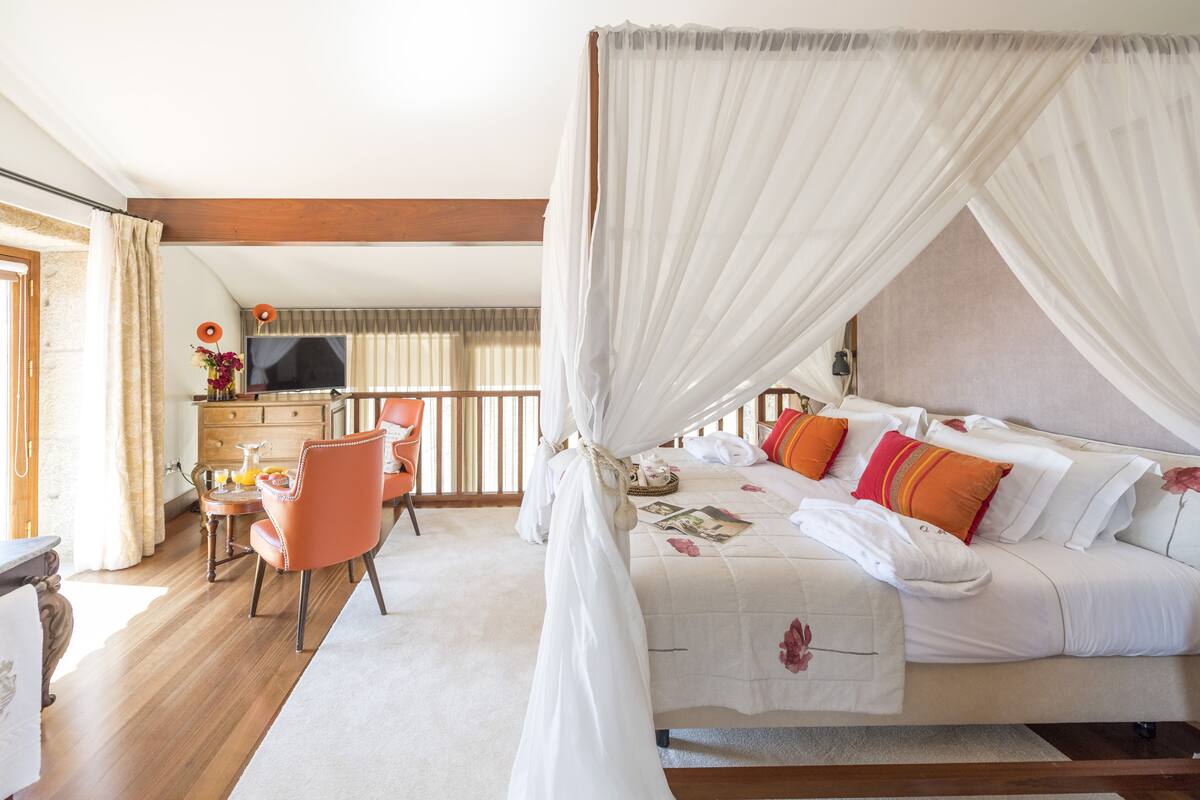 Une chambre à coucher avec un lit à baldaquin, un bureau avec une chaise et un téléviseur.