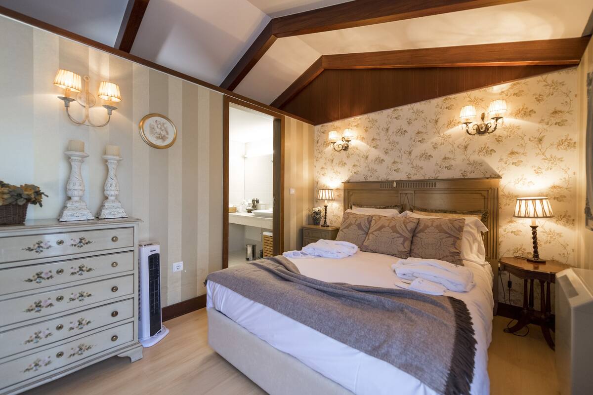 Une chambre à coucher avec un grand lit, des lampes de chevet, une commode et un miroir.