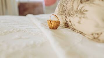 Una pequeña cesta tejida sobre una cama con un cojín estampado con motivos florales.