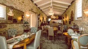 A dining area with stone walls, chandeliers, and a mix of upholstered and wooden chairs. - Quinta Do Monteverde (Viana do Castelo)