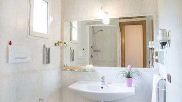 A modern bathroom with a glass sink, a mirror, a shower, and a towel rack.
