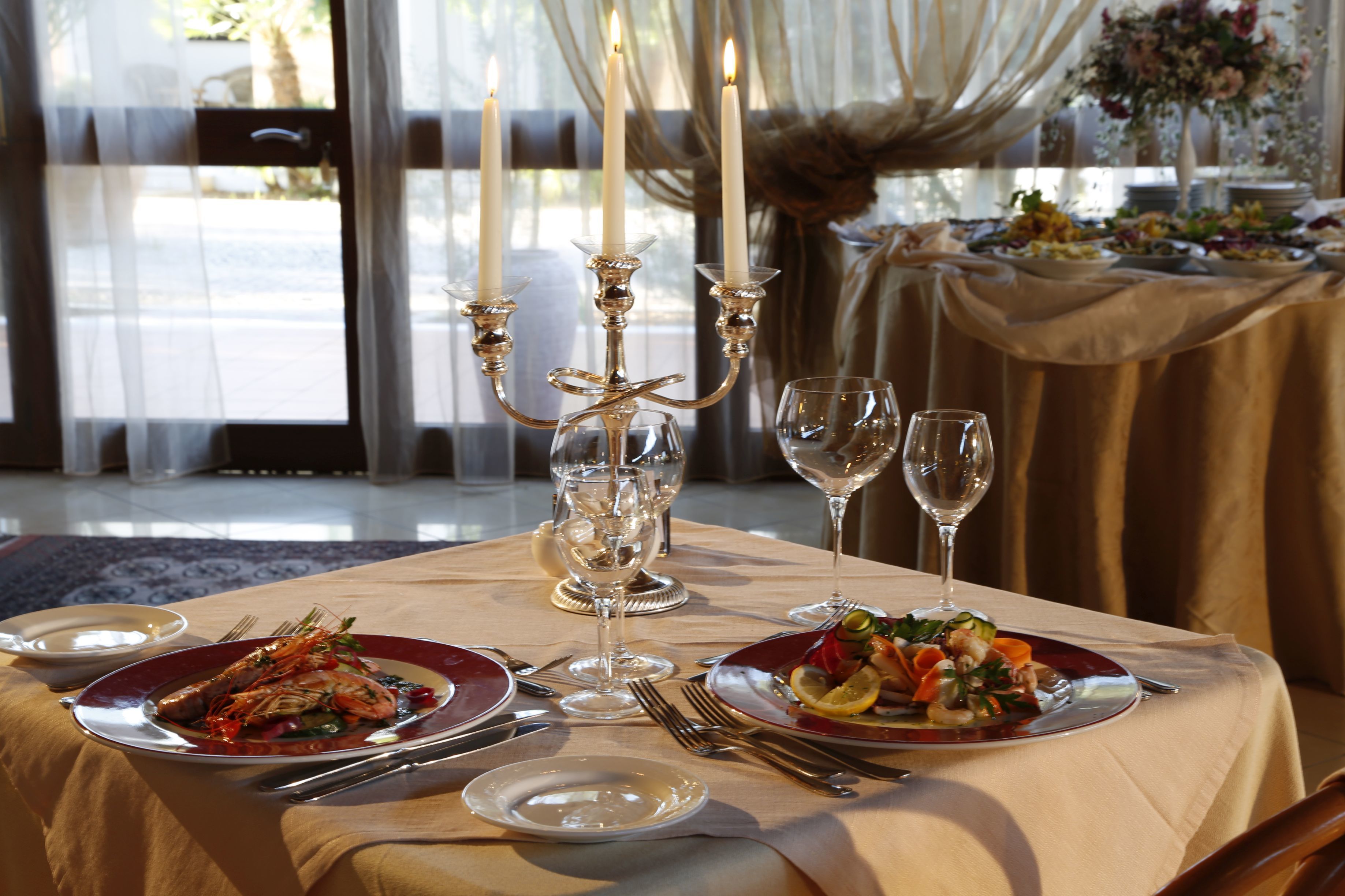 Un tavolo imbandito con piatti di cibo, bicchieri di vino e un candelabro.