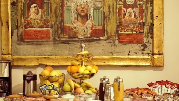 A table with various food items and a painting above it. - Premier Hotel (Skopje)