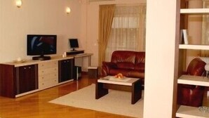 A living room with a leather sofa, a coffee table, a TV, and a small cabinet. - Premier Hotel (Skopje)