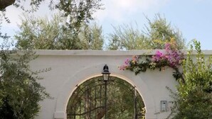A stone pathway leading to a white wall with an arched entrance. - Tenuta Centoporte (Giurdignano)