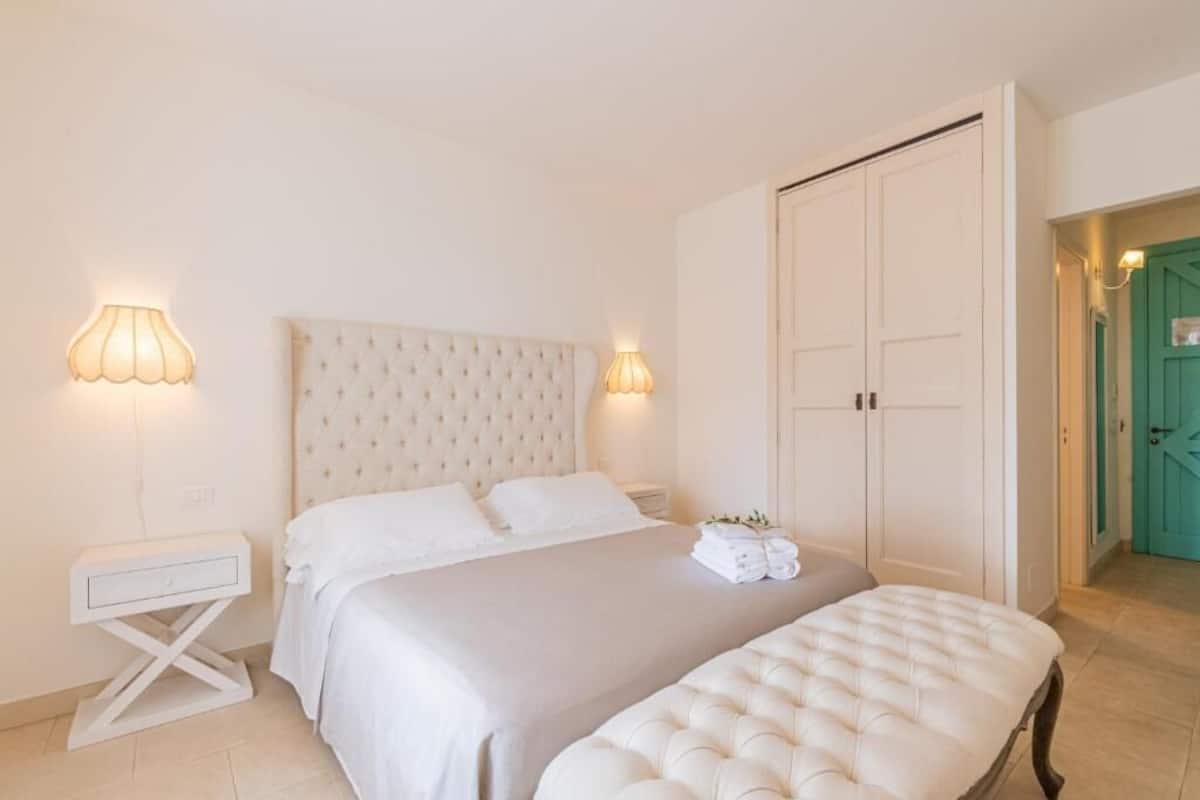 A bedroom with a large bed, bedside tables, and a wardrobe.
