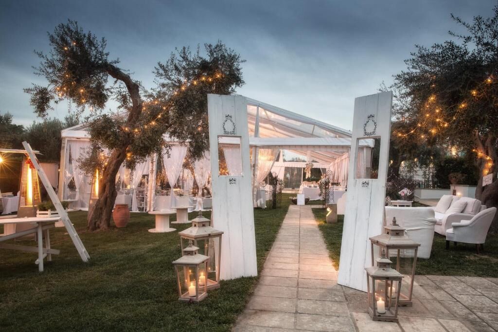 An outdoor event space with a tented area, white furniture, and lanterns.