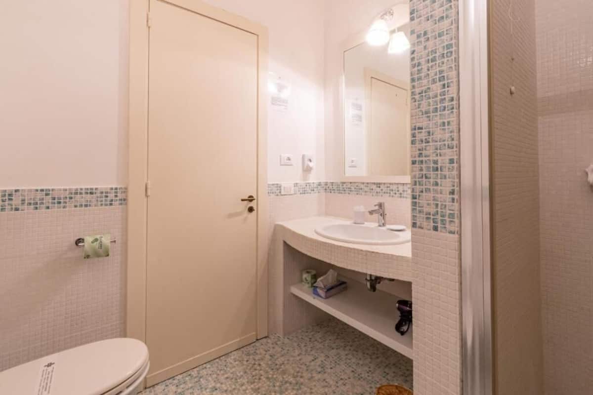 A bathroom with a toilet, sink, and mirror.