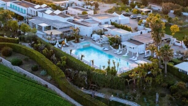 An aerial view of a resort with multiple buildings, a swimming pool, and landscaped gardens. - Tenuta Centoporte (Giurdignano)