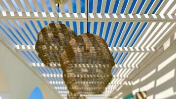 Techo con estructura de celosía blanca y lámparas colgantes tejidas.
